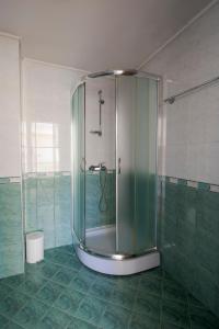 y baño con ducha de cristal y azulejos verdes. en Семеен хотел Кристал en Smolyan