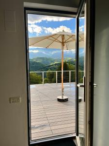 una puerta abierta a un balcón con sombrilla en Casa Stelar - A breathtaking view, en Moieciu de Jos