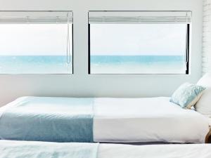 a white bedroom with two windows and a bed at &SUN Terrace house in Yokosuka