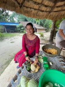 a woman sitting on a table with a plate of food at Good Karma Homestay in Bhurkīā