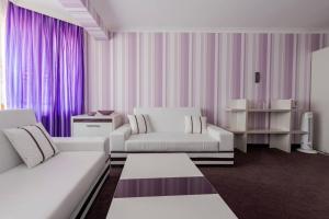 a living room with two white couches and purple curtains at Семеен хотел Кристал in Smolyan +60 photos