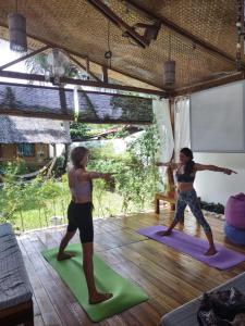 Duas pessoas estão a fazer ioga numa sala de estar. em Lunazul Guesthouse em San Vicente