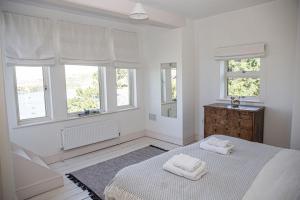 a white bedroom with two towels on a bed at Main House at White Horses, Bantham, South Devon with panoramic sea views across to Burgh Island in Bigbury on Sea