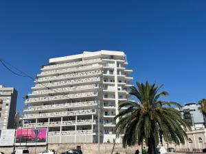 um edifício branco alto com uma palmeira em frente em Marisabella Suite Spa 5 em Bari