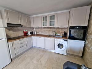 a kitchen with white cabinets and a washing machine at Holiday home Barci in Crikvenica