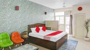 - une chambre avec un lit et deux chaises orange dans l'établissement OYO Krishna Orchid Near Noida Sector 81 Metro Station, à Noida