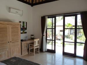 a bedroom with a bed and a desk and a window at Taman Dewi Sri Villa et Bungalow in Pemuteran