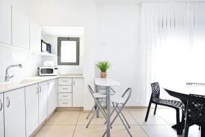 a kitchen with white cabinets and a table and chairs at Perfect Location 2BR in Reines by HolyGuest in Tel Aviv