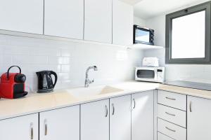 a white kitchen with a sink and a microwave at Perfect Location 2BR in Reines by HolyGuest in Tel Aviv