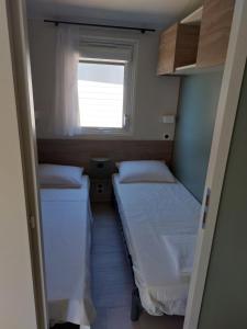 2 camas en una habitación pequeña con ventana en L'arbre perché, en Saint-Raphaël