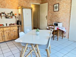 een keuken met een witte tafel en stoelen bij Au dessus des arcades in Vic-Fezensac