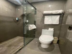 a bathroom with a toilet and a glass shower at VX Hotel Tianjin West Yongyang Road Florentia Town in Wuqing
