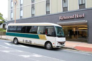 un autobus bianco parcheggiato di fronte a un edificio di Richmond Hotel Narita a Narita