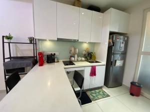 a small kitchen with white cabinets and a refrigerator at Islamic Santai Santai Homestay - Centrus Soho Cyberjaya in Cyberjaya +3 photos