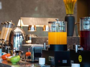 a kitchen counter with a blender with orange liquid in it at GreenTree Eastern Hotel Tianjin Wuqing Wanda Plaza in Wuqing