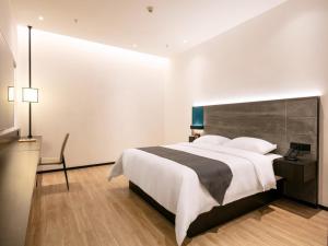 a bedroom with a large white bed and a desk at Geli Hotel Nanning East Railway Station in Nanning