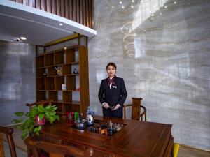 uma mulher de fato ao lado de uma mesa em GreenTree Eastern Hotel Hebi Jun County Passenger Station em Xun