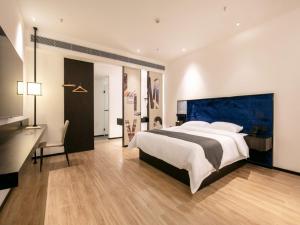 a large bedroom with a large bed and a desk at Geli Hotel Nanning East Railway Station in Nanning
