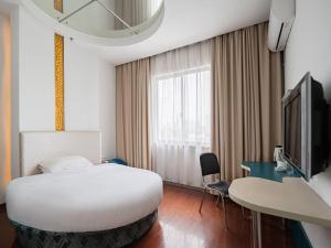 Habitación de hotel con cama, escritorio y TV. en GreenTree Inn Express Hotel North Huaihai Road, en Huai'an
