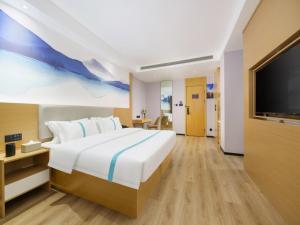 um quarto com uma cama grande e uma televisão de ecrã plano em VX Hotel Dalian Zhoushuizi Airport em Dalian