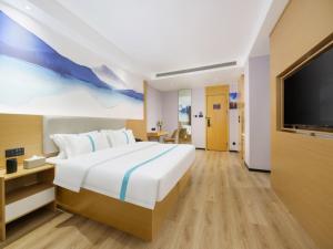 a bedroom with a large bed and a flat screen tv at VX Hotel Dalian Zhoushuizi Airport in Dalian