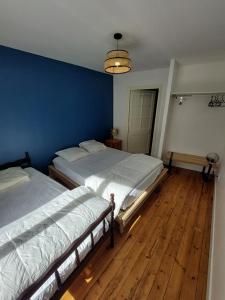two beds in a bedroom with a blue wall at Maison plein centre COULON MARAIS POITEVIN in Coulon