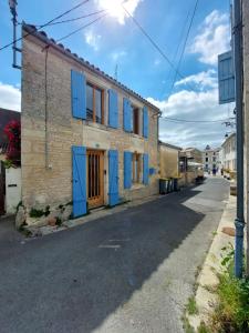 an old house with blue shutters on a street at Maison plein centre COULON MARAIS POITEVIN in Coulon