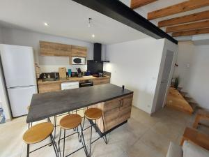 a kitchen with a counter and some stools in it at Maison plein centre COULON MARAIS POITEVIN in Coulon +15 photos