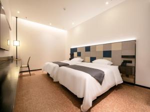 um quarto com uma grande cama branca e uma secretária em Geli Hotel Nanning East Railway Station em Nanning