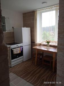 uma cozinha com um frigorífico, uma mesa e uma janela em Viešnagė name prie miško. em Magučiai