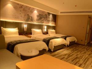 une chambre d'hôtel avec trois lits et un canapé dans l'établissement GreenTree Eastern Hotel Dezhou Qingyun Yingcai Road Financial Building, à Dezhou