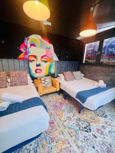 two beds in a room with a mural on the wall at The Melville Hotel by Rokxy- Kings Cross in London
