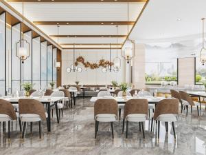 un restaurant avec des tables blanches, des chaises et des fenêtres dans l'établissement GreenTree Eastern Hotel Jiangsu Wanda Plaza Ocean University Huangguoshan, à Lianyungang
