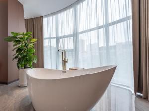 a white tub in a bathroom with a large window at VX Hotel Xuzhou Suining Remin Road in Suining