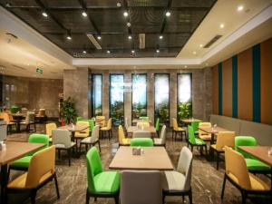 um restaurante com mesas e cadeiras verdes e janelas em GreenTree Eastern Hotel Chongqing Jiefangbei Children's Hospital em Chongqing