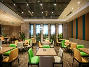 a restaurant with tables and green chairs and windows at GreenTree Eastern Hotel Chongqing Jiefangbei Children's Hospital in Chongqing