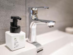 a bathroom sink with a soap dispenser next to a faucet at Deep Sleep Hotel Hangzhou Dajiang East Haide Xingang Center in Hangzhou