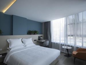a bedroom with a large white bed and a window at Geli Hotel Suqian Shuyang Yingbin Avenue in Shuyang