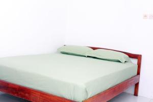 a wooden bed with two pillows on top of it at Liahz Lodge in Kelimutu