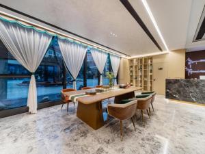 una sala da pranzo con tavolo, sedie e finestre di GreenTree Eastern Hotel Nanjing Jiangning University a Jiangning