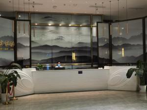 a woman is sitting at a counter in a lobby at GreenTree Eastern Hotel Ji'an City Suichuan Industrial Park in Suichuan