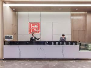 two people standing at a counter in a lobby at GreenTree Eastern Hotel Chongqing Jiefangbei International Airport Lushan Subway Station in Chongqing