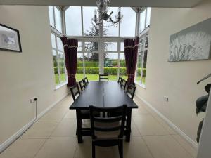 a dining room with a table and chairs and windows at Dovecote Lodge on the 5 star Lough Erne Resort in Ballycassidy