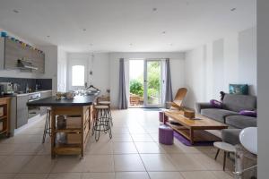 eine Küche und ein Wohnzimmer mit einem Sofa und einem Tisch in der Unterkunft La Guinebaudière - Maison avec terrasse in Naveil