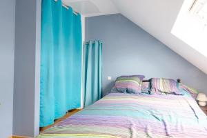 1 dormitorio con 1 cama con cortinas azules en La Guinebaudière - Maison avec terrasse, en Naveil