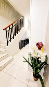 a white hallway with stairs and a vase of flowers at Bels Boarding House (Kost) in Pumpangsineng