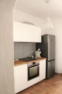 a kitchen with white cabinets and a stainless steel refrigerator at CasaMare. Orbetello centro storico. in Orbetello