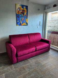ein rotes Sofa im Wohnzimmer mit einem Gemälde in der Unterkunft Appartement in Saint Cyprien Plage