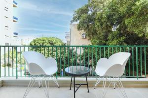 2 weiße Stühle und ein Tisch auf dem Balkon in der Unterkunft The Adam's by HolyGuest in Tel Aviv