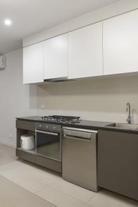 eine Küche mit Küchengeräten aus Edelstahl und weißen Schränken in der Unterkunft Quick Aces Premium in Melbourne